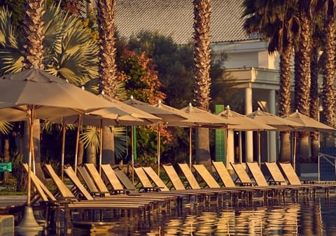 Espreguiçadeiras e guarda-sóis à beira da piscina do Jardins de Jurema ao entardecer