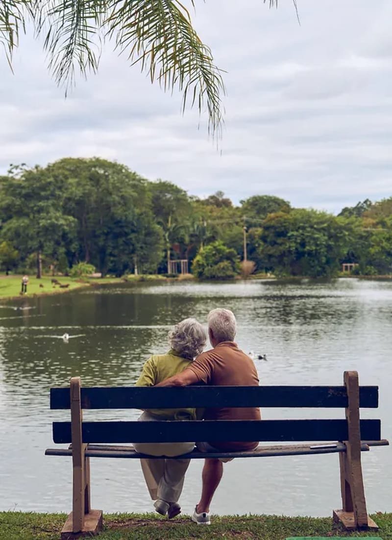 Casal sentado em um banco contemplando o lago do Lagos de Jurema