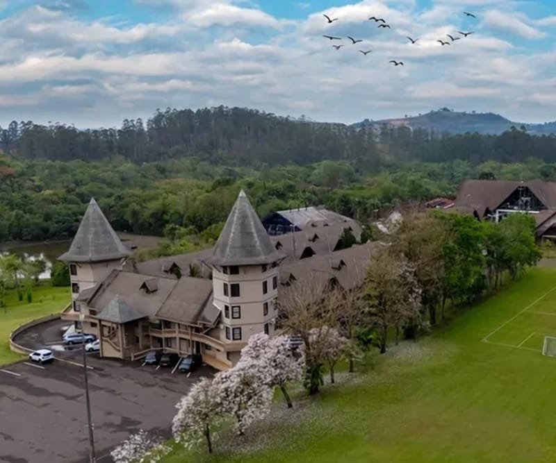 Vista aérea do edifício principal do Lagos de Jurema, com torres pontiagudas, gramado e mata